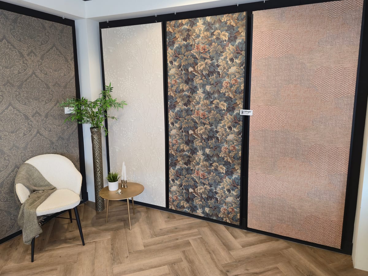 Vier grote behangpanelen in de showroom, met een witte stoel en een gouden bijzettafel op een visgraatvloer