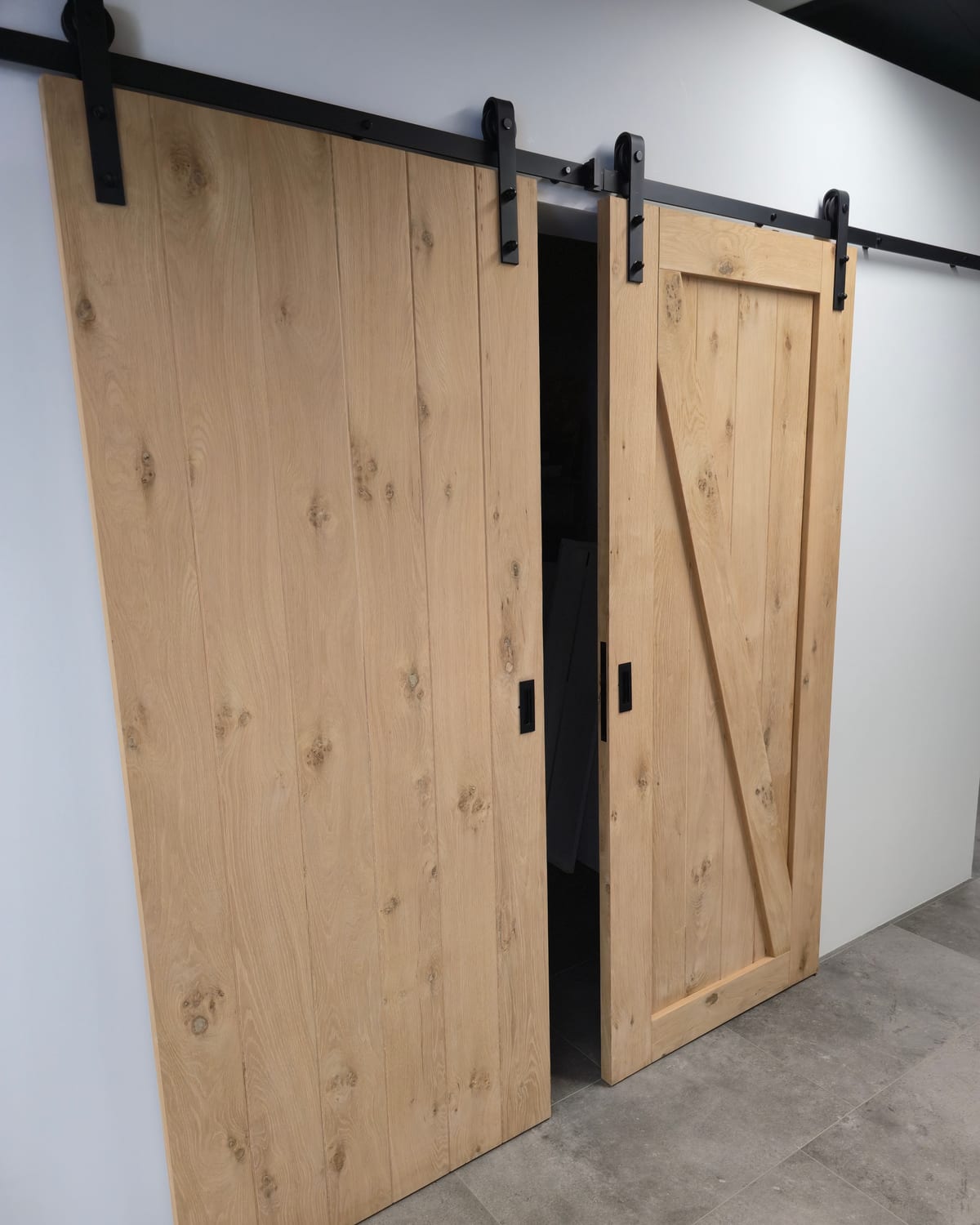 Twee houten schuifdeuren aan een zwarte rail in de showroom