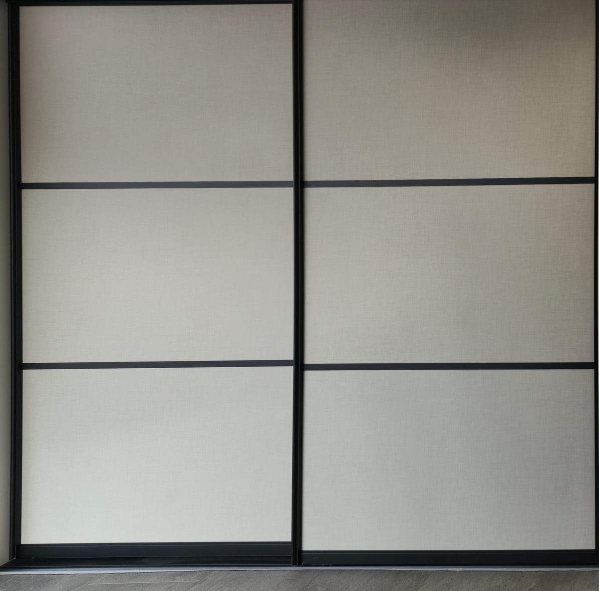 Schuifdeuren van MW kasten (raumplus) in de showroom: lichte panelen met linnenstructuur en zwarte tussenstrips
