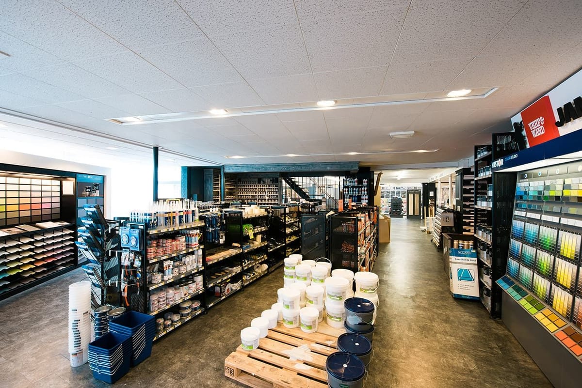 De verfafdeling van de winkel met kleurenwanden en verfblikken in de schappen