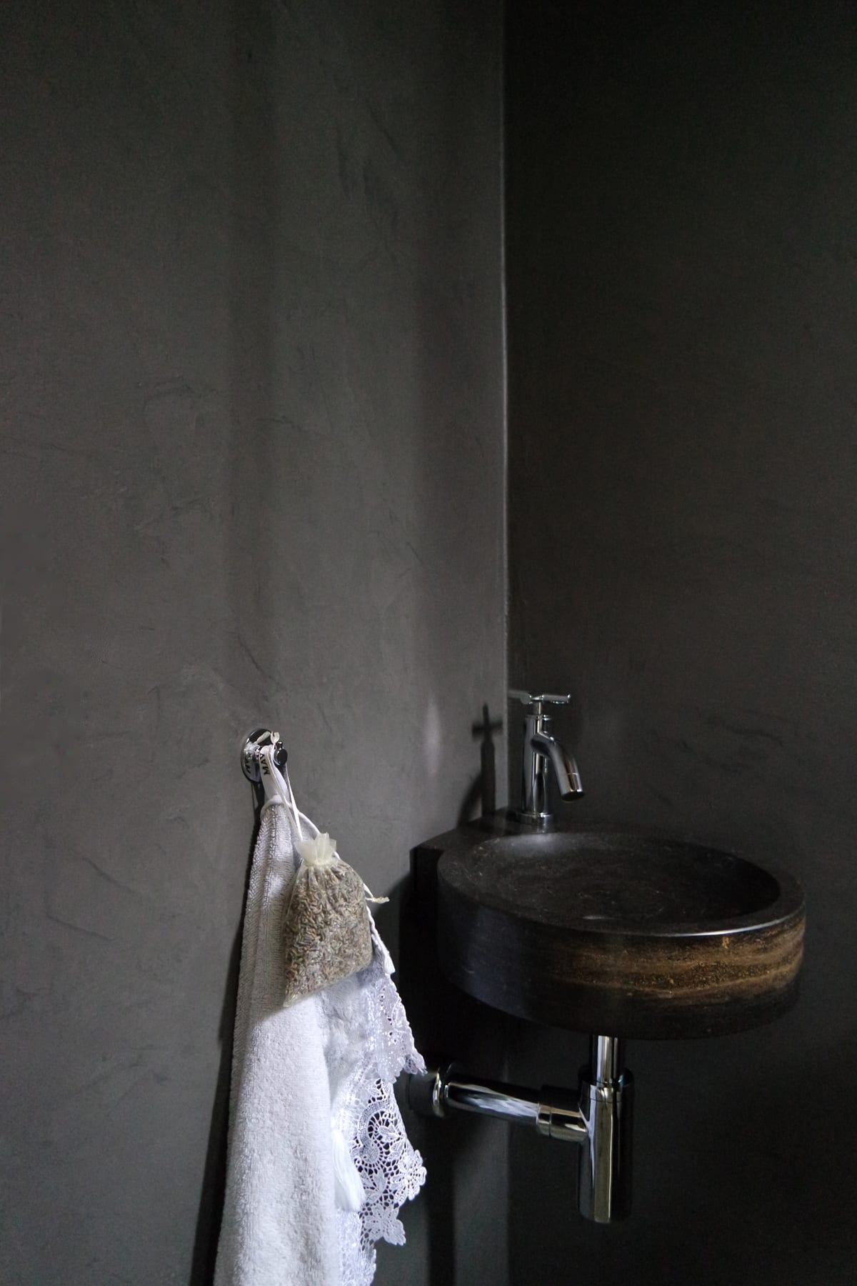 Toilet met grijs gestuukte wanden in Pro Finish Stucco, een natuurstenen fonteintje en een chromen kraan