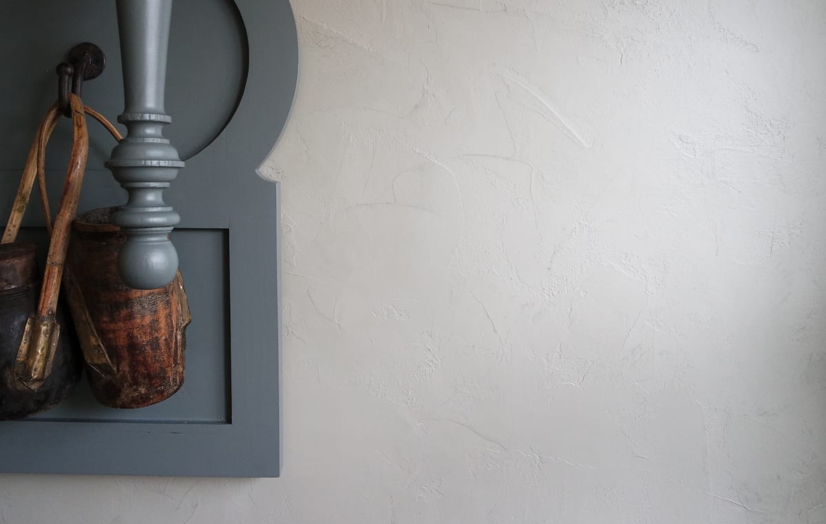 Witte wand in Pro Finish Stucco met een lichte structuur, met een grijze houten wandconsole en een mand
